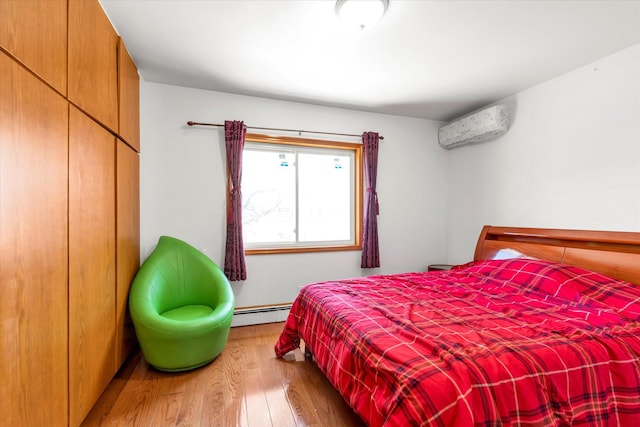 bedroom featuring a baseboard radiator, a closet, a wall mounted air conditioner, and wood finished floors