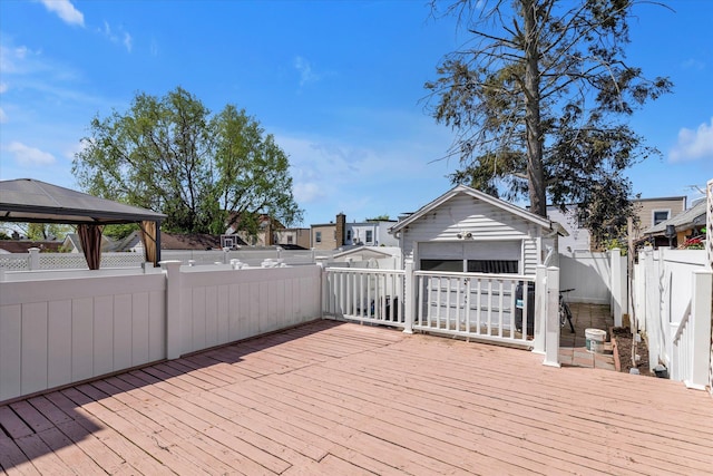 wooden deck with a residential view, a gazebo, a garage, a fenced backyard, and an outdoor structure