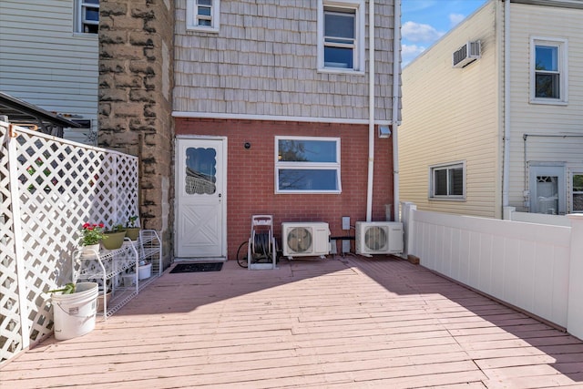 exterior space featuring brick siding, ac unit, mansard roof, and a deck
