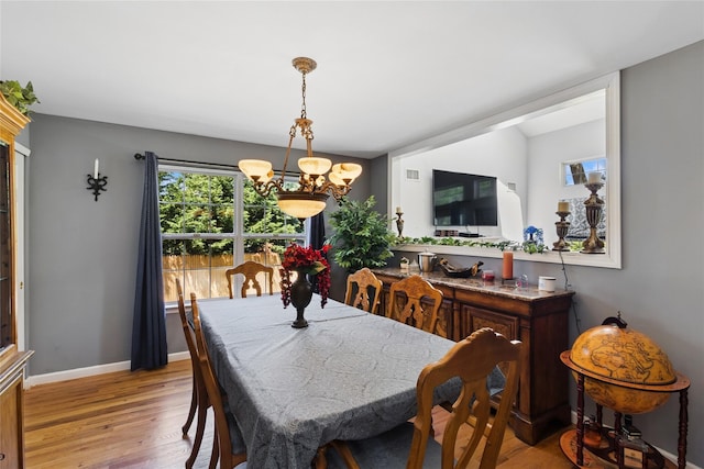 dining space with an inviting chandelier, baseboards, and wood finished floors
