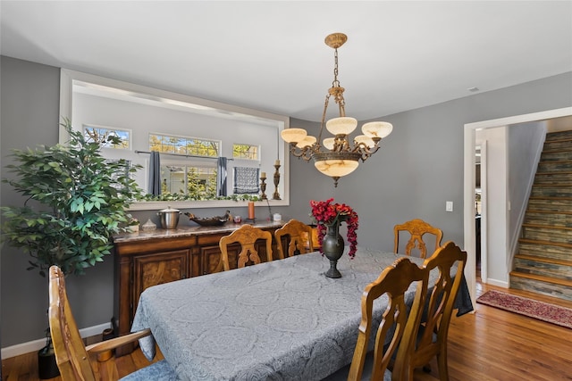 dining area with stairs, baseboards, an inviting chandelier, and wood finished floors