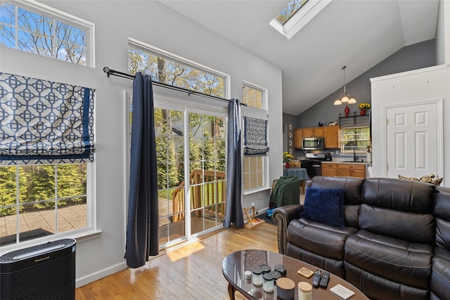 living room with light wood-style floors, high vaulted ceiling, baseboards, heating unit, and a skylight