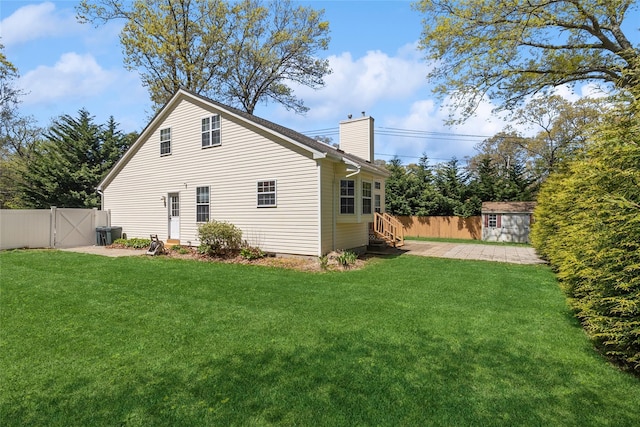 back of house with a chimney, a lawn, a gate, fence, and entry steps