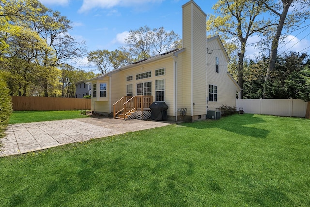 back of house featuring a lawn, fence, a chimney, and central AC unit