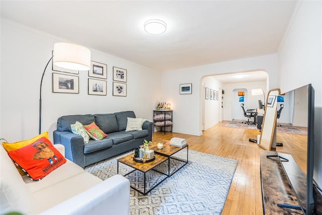 living area featuring wood-type flooring, arched walkways, and baseboards