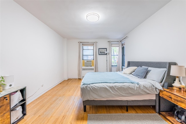 bedroom featuring radiator heating unit, baseboards, and light wood-style flooring