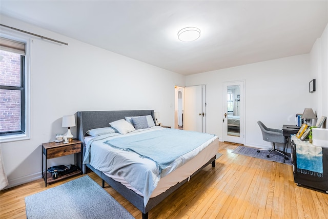 bedroom featuring baseboards, multiple windows, and light wood finished floors