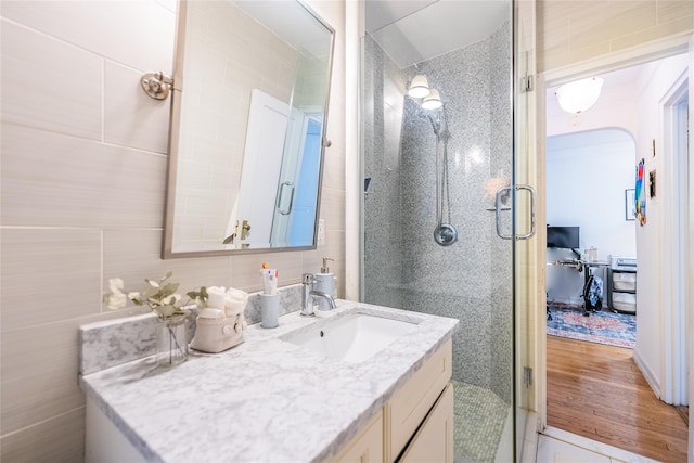full bath with tile walls, a shower stall, and vanity