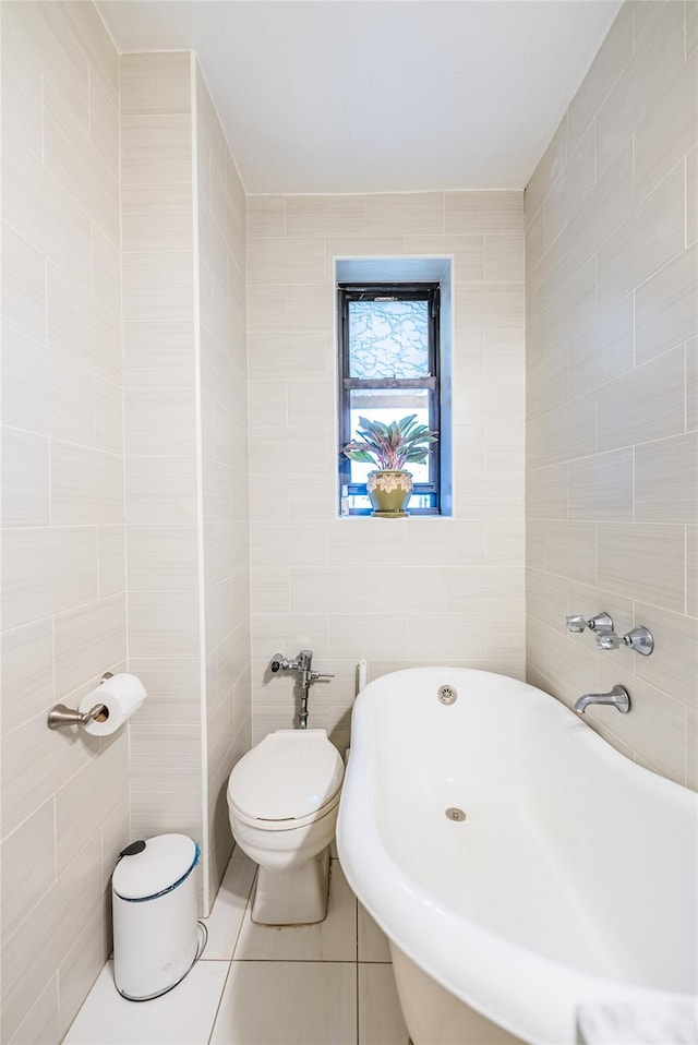 full bathroom with a freestanding bath, tile walls, tile patterned flooring, and toilet