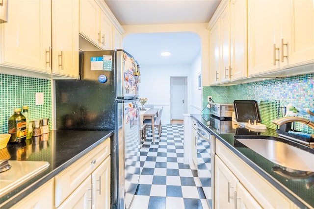 kitchen with tile patterned floors, appliances with stainless steel finishes, decorative backsplash, and a sink