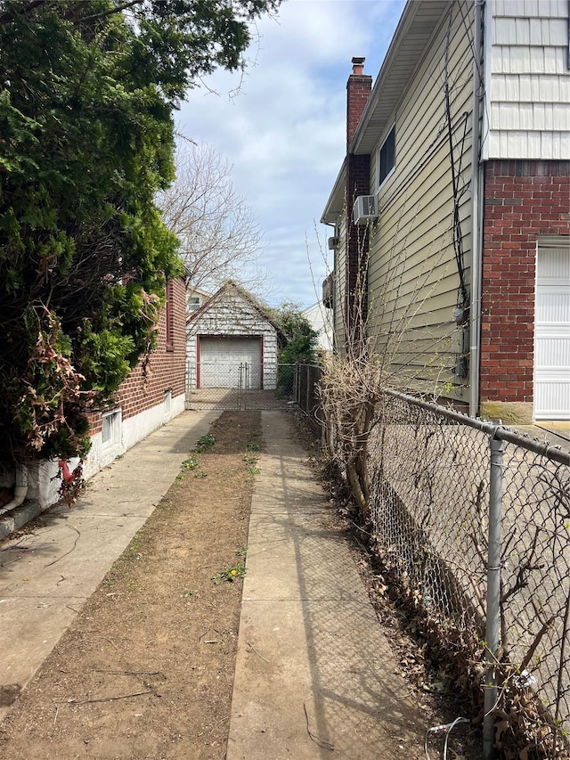 view of property exterior featuring brick siding, a detached garage, concrete driveway, and fence