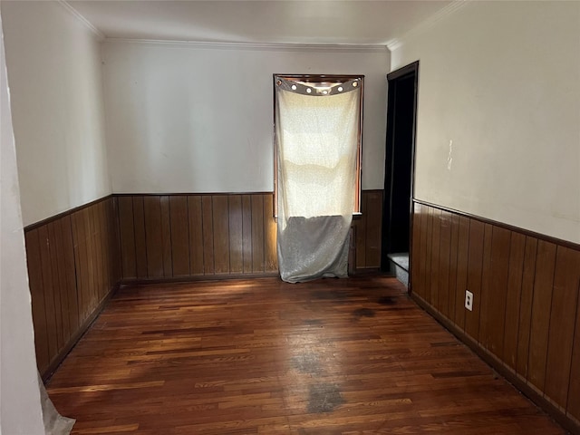 spare room with dark wood-style floors, ornamental molding, and wainscoting