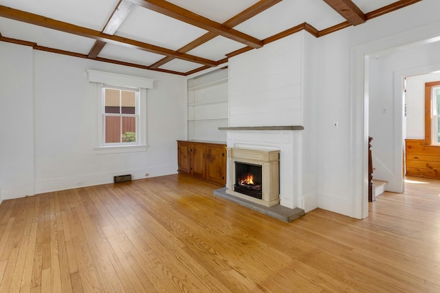 unfurnished living room with light wood finished floors, a fireplace, a healthy amount of sunlight, and coffered ceiling