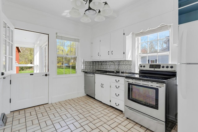 kitchen with dark countertops, a notable chandelier, appliances with stainless steel finishes, a sink, and white cabinetry