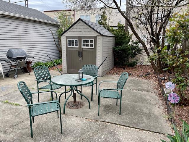 view of patio / terrace with grilling area, an outbuilding, outdoor dining space, and a storage unit