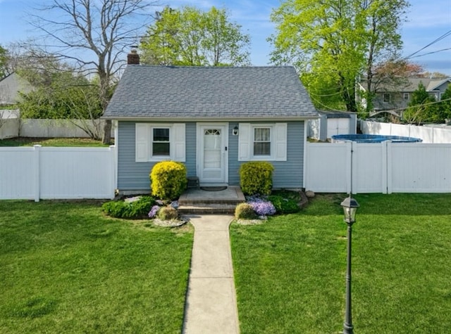 view of front of home featuring a chimney, a front yard, a shingled roof, and a fenced backyard
