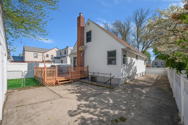 1041 N 6th St, New Hyde Park, NY 11040 - rear view of property featuring a wooden deck, a fenced backyard, a patio, a chimney, and a gate