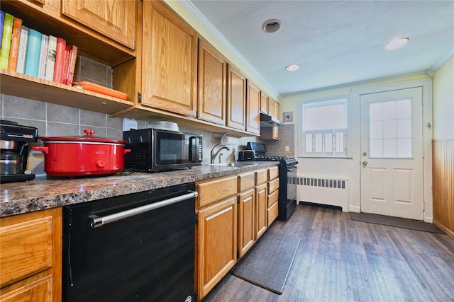 kitchen with tasteful backsplash, a sink, dark wood-style floors, black appliances, and radiator heating unit