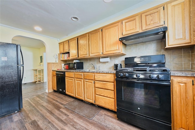 kitchen with crown molding, arched walkways, black appliances, under cabinet range hood, and wood finished floors