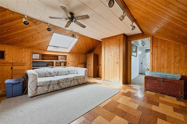 bedroom featuring rail lighting, wooden walls, a ceiling fan, and vaulted ceiling
