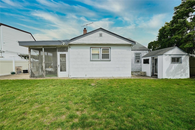 back of house with fence, a yard, a sunroom, and a storage shed