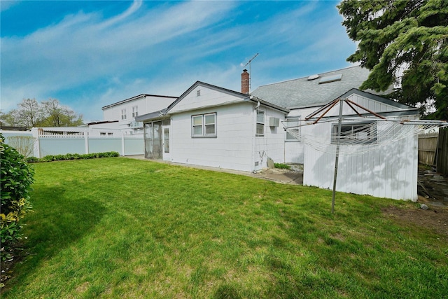 back of property featuring a chimney, fence, and a lawn