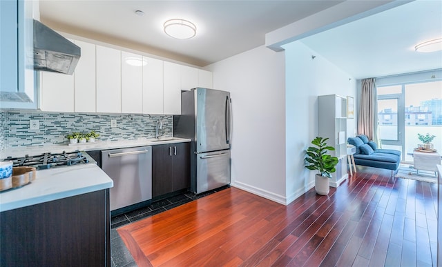 kitchen with dark wood-style floors, light countertops, extractor fan, tasteful backsplash, and appliances with stainless steel finishes