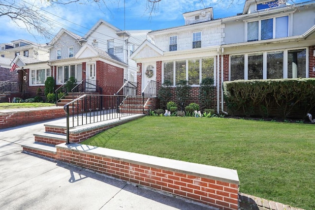 view of front facade with brick siding and a front lawn