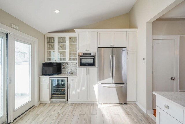 kitchen with a wealth of natural light, lofted ceiling, beverage cooler, and freestanding refrigerator