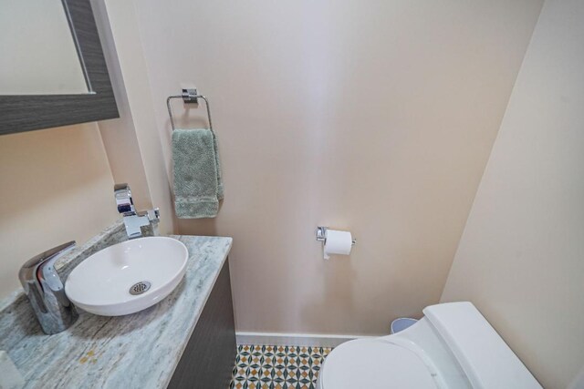 bathroom featuring baseboards, toilet, and vanity