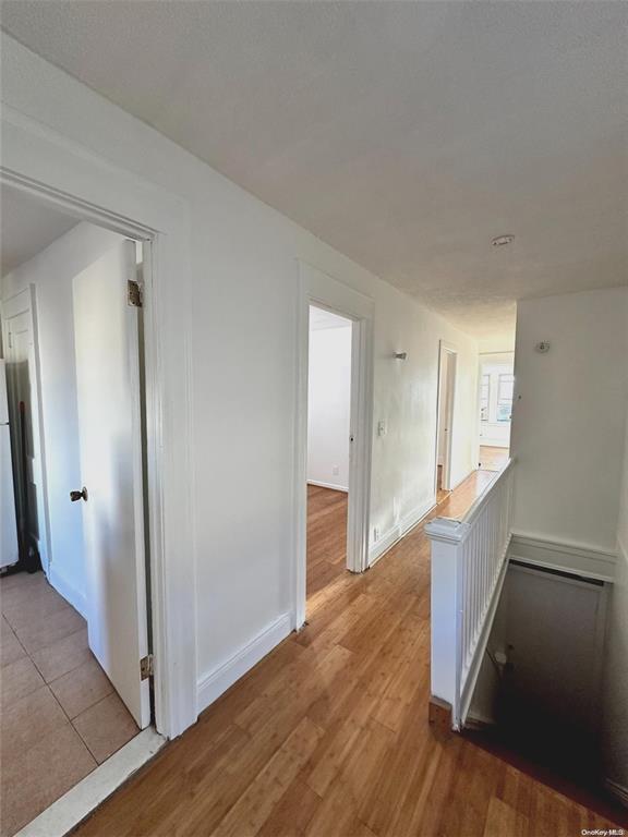 88-39 186th St, Hollis, NY 11423 - hall featuring light wood-style flooring, baseboards, and an upstairs landing