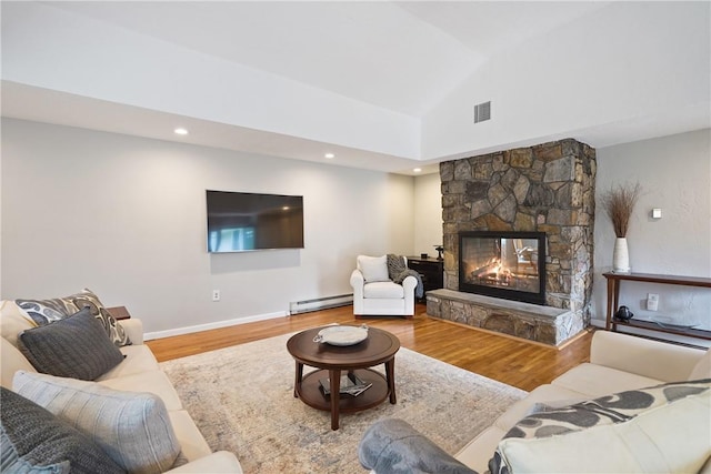 living area featuring a baseboard radiator, wood finished floors, visible vents, and a fireplace