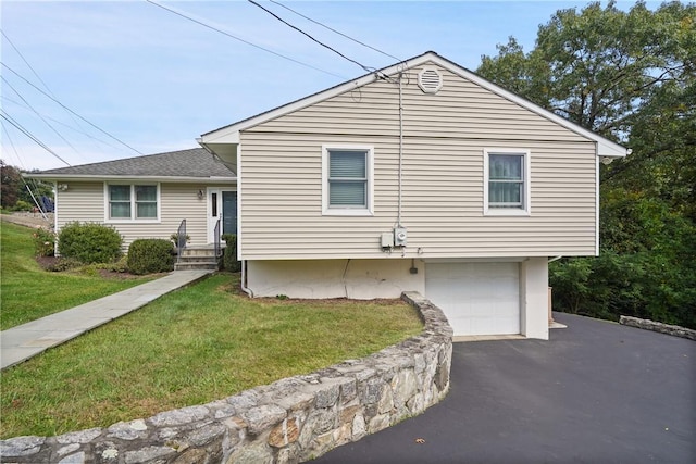 tri-level home with an attached garage, a shingled roof, a front yard, and aphalt driveway