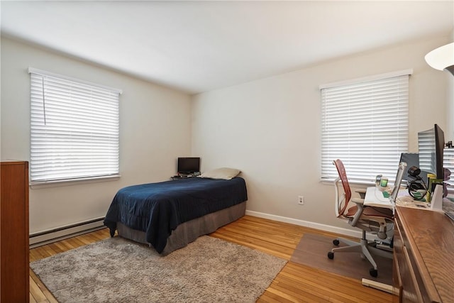 bedroom featuring baseboard heating, baseboards, and wood finished floors