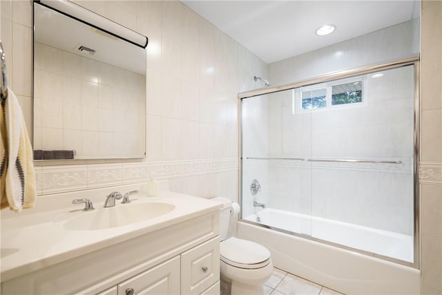 bathroom featuring enclosed tub / shower combo, visible vents, toilet, vanity, and tile walls