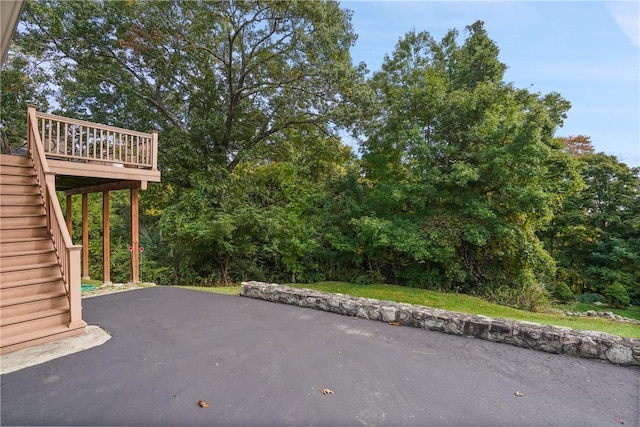 view of patio / terrace with a wooden deck, stairway, and aphalt driveway