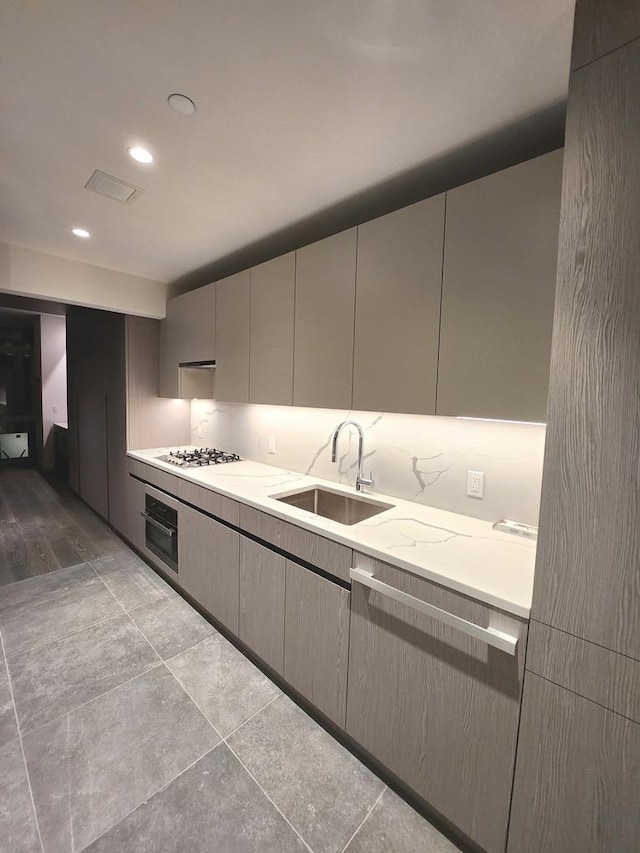 kitchen with light countertops, gas stovetop, oven, and a sink