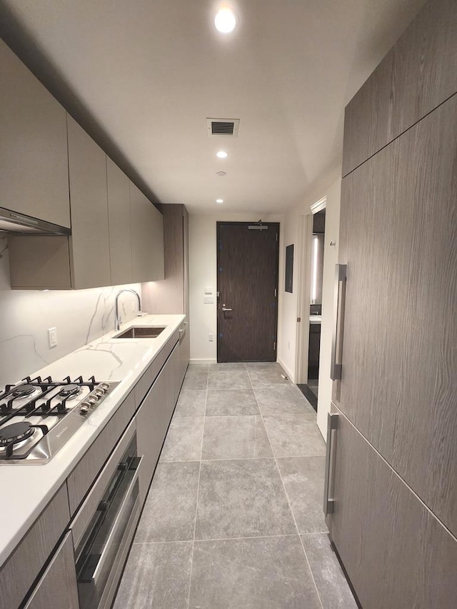 kitchen featuring stainless steel appliances, light countertops, gray cabinetry, and a sink