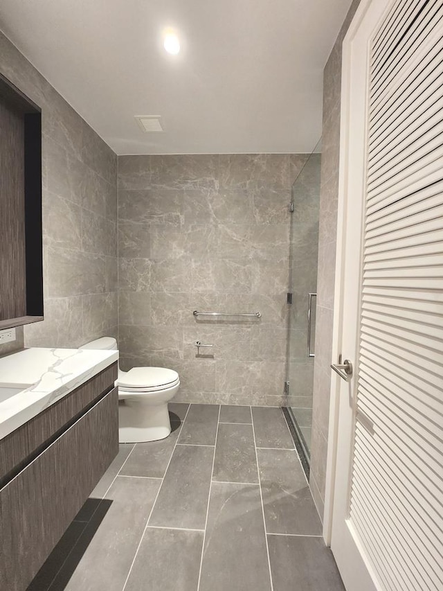 full bath featuring vanity, toilet, a stall shower, and tile walls