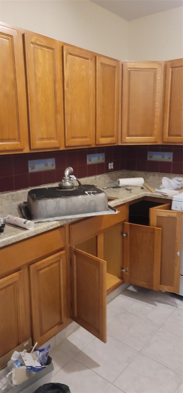 kitchen with a sink, brown cabinets, and tasteful backsplash