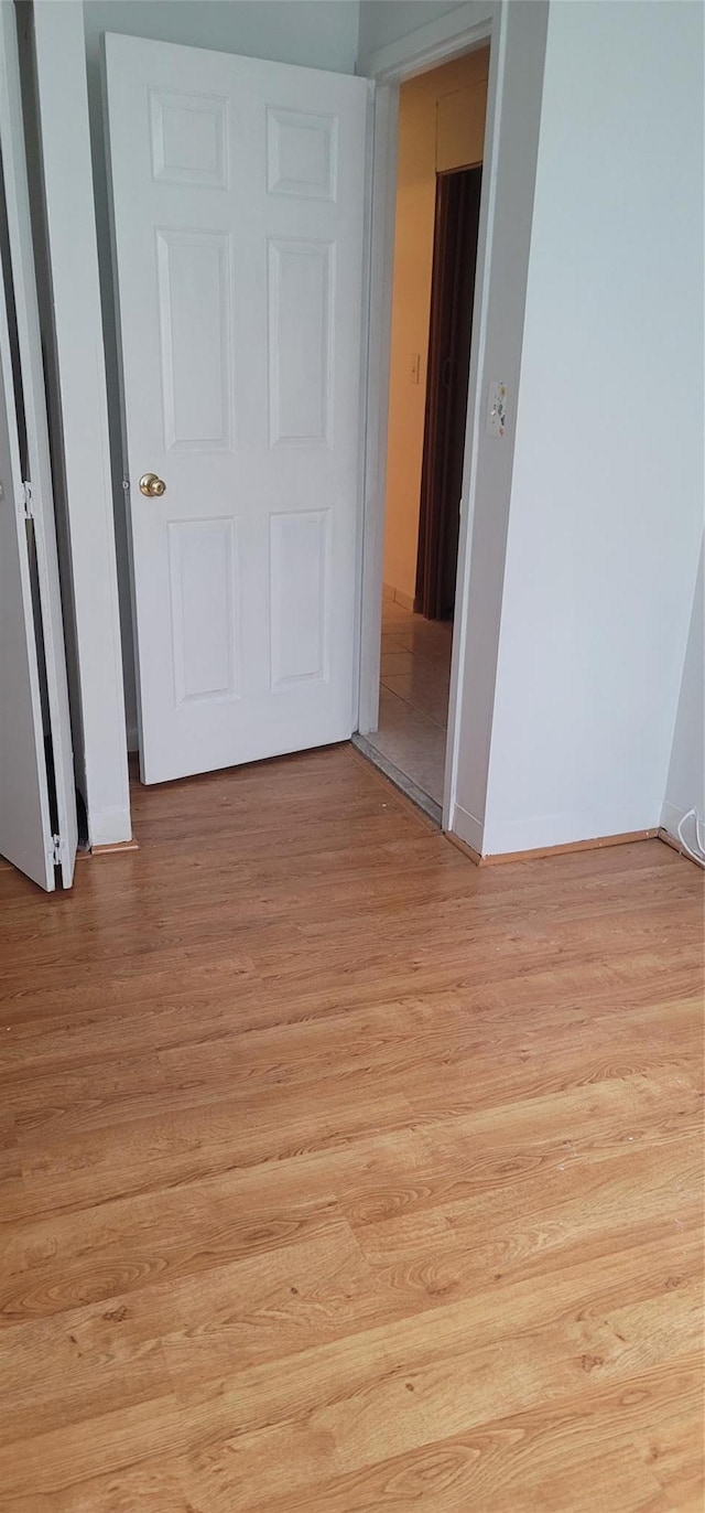 spare room with light wood-style flooring and baseboards