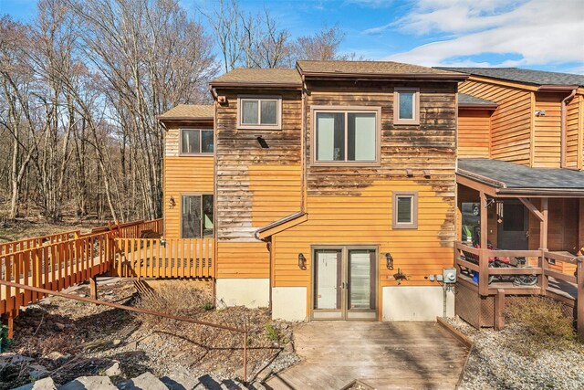 rear view of property featuring a wooden deck and a shingled roof