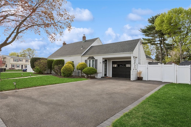 view of front of house with a chimney, a gate, driveway, a front yard, and an attached garage