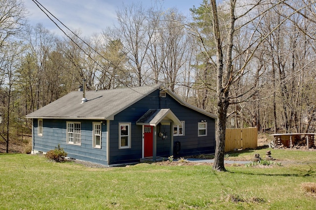 view of front of house with fence, a front lawn, and roof with shingles