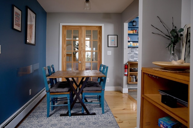 dining area featuring baseboards, wood finished floors, french doors, and a baseboard radiator