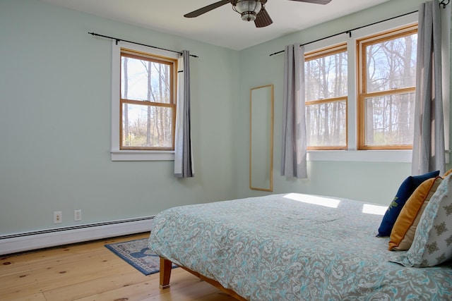 bedroom with a ceiling fan, wood finished floors, and a baseboard radiator