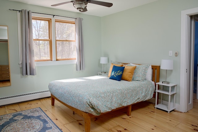 bedroom with ceiling fan, baseboards, baseboard heating, and wood-type flooring