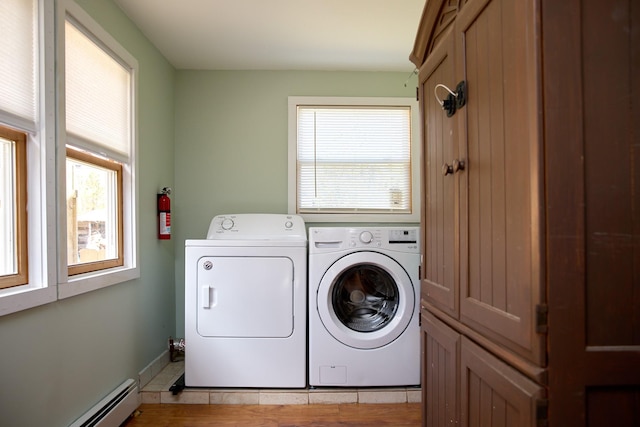 clothes washing area featuring baseboards, a baseboard heating unit, cabinet space, and independent washer and dryer