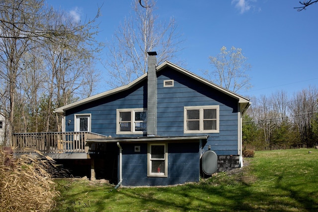 back of property with a deck, a yard, a chimney, and heating fuel