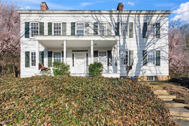 colonial-style house with a chimney and covered porch